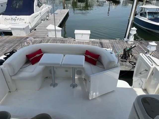 Slide: The Image of 2000 Cruisers Yachts 4450 Express Motoryacht with docked seating area and red cushions. - 8