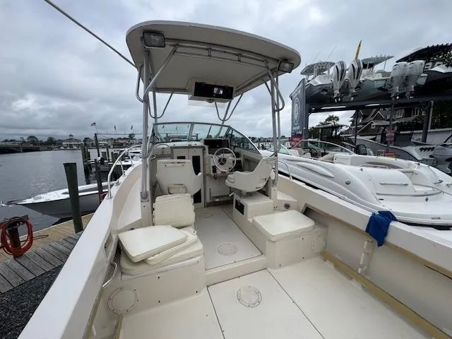 Slide: The Image of 1992 Grady-White Explorer 244 boat interior at a marina, featuring seating and steering console. - 10