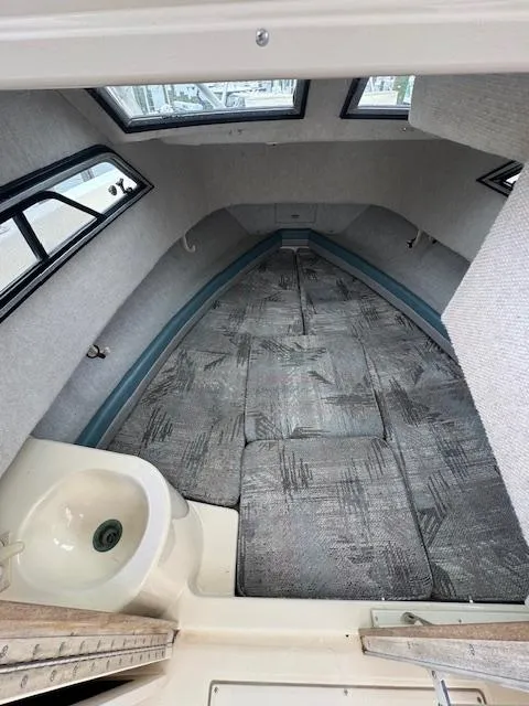 Slide: The Image of 1992 Grady-White Explorer 244 cabin interior with cushioned seating and small sink. - 16