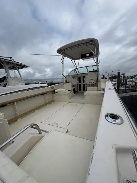 Slide: The Image of 1992 Grady-White Explorer 244 boat with open deck and canopy, docked under cloudy skies. - 9