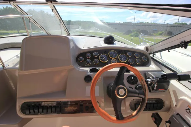 Slide: The Image of 2001 Cruisers Yachts 3470 Express helm with gauges and wooden steering wheel. - 12