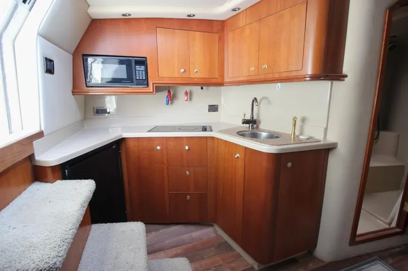 Slide: The Image of 2001 Cruisers Yachts 3470 Express kitchen with wood cabinets, microwave, and sink. - 17