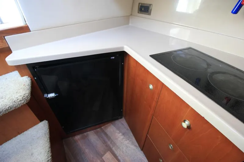 Slide: The Image of 2001 Cruisers Yachts 3470 Express kitchen with stove, fridge, and wooden cabinets. - 18