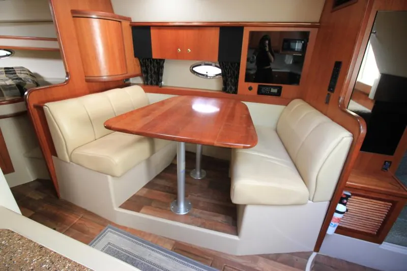 Slide: The Image of 2001 Cruisers Yachts 3470 Express interior with dining area, wooden table, and beige seating. - 19