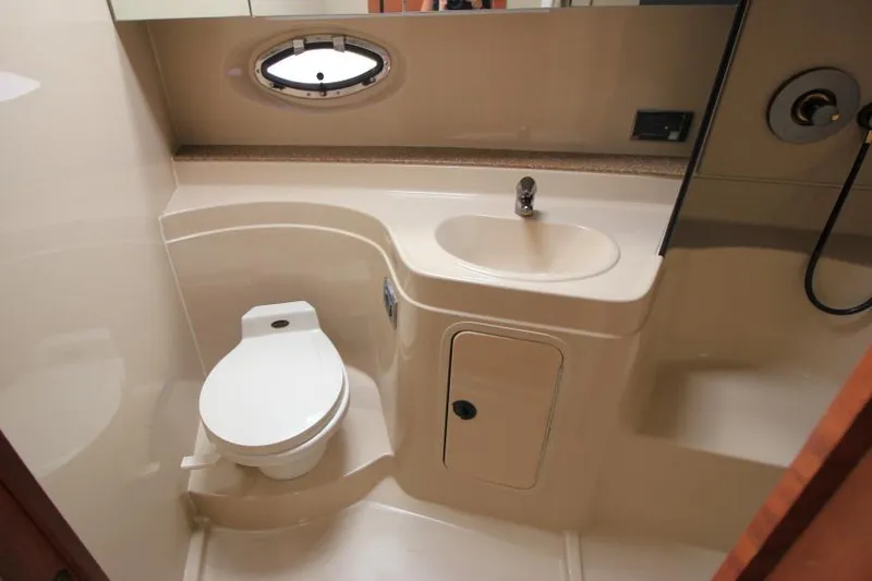 Slide: The Image of 2001 Cruisers Yachts 3470 Express bathroom with toilet, sink, and porthole window. - 24