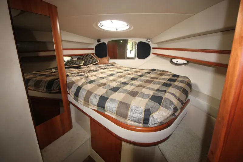 Slide: The Image of 2001 Cruisers Yachts 3470 Express cabin with bed, mirror, and porthole window. - 25