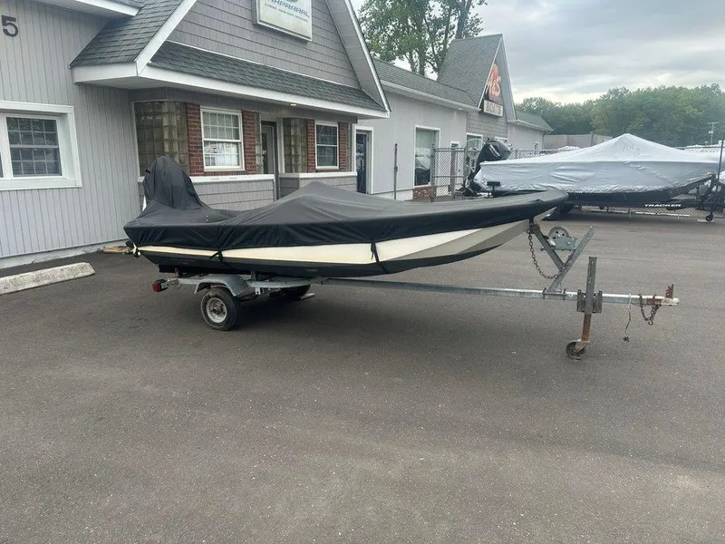 Slide: The Image of 1983 Boston Whaler Sport boat covered on trailer outside a building. - 12