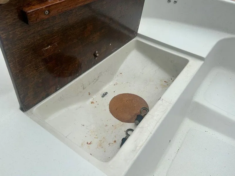 Slide: The Image of 1983 Boston Whaler Sport storage compartment with wooden lid and visible hardware. - 18