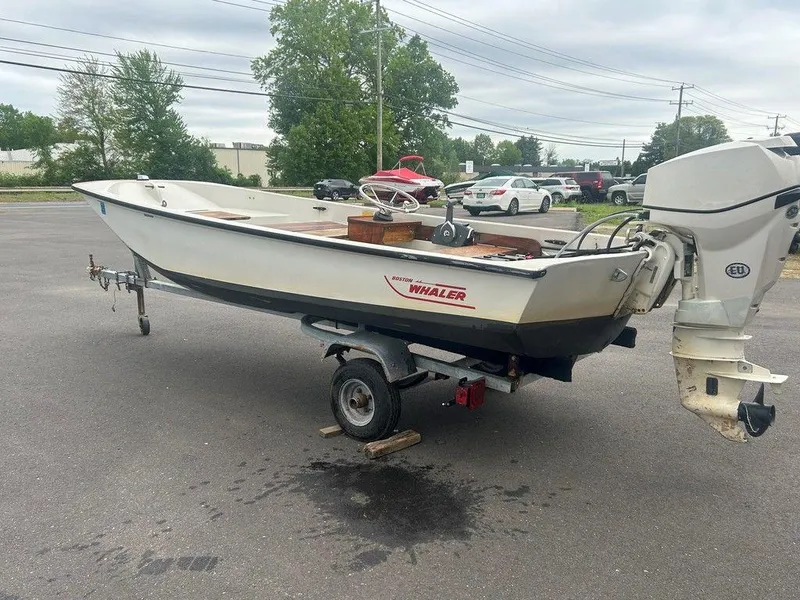 Slide: The Image of 1983 Boston Whaler Sport boat on trailer, parked in a lot with cars and trees. - 3
