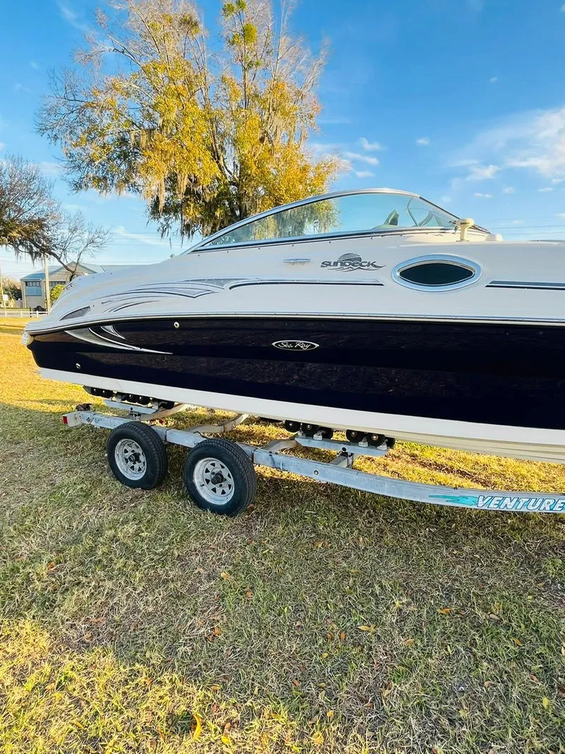 Slide: The Image of 2005 Sea Ray 240 Sundeck boat on trailer, parked on grass under a clear sky. - 1
