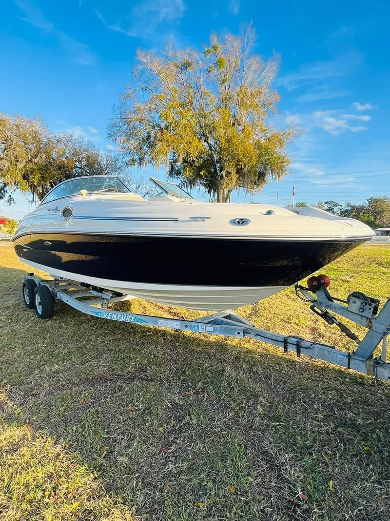 Slide: The Image of 2005 Sea Ray 240 Sundeck boat on trailer, parked on grass under clear blue sky. - 5