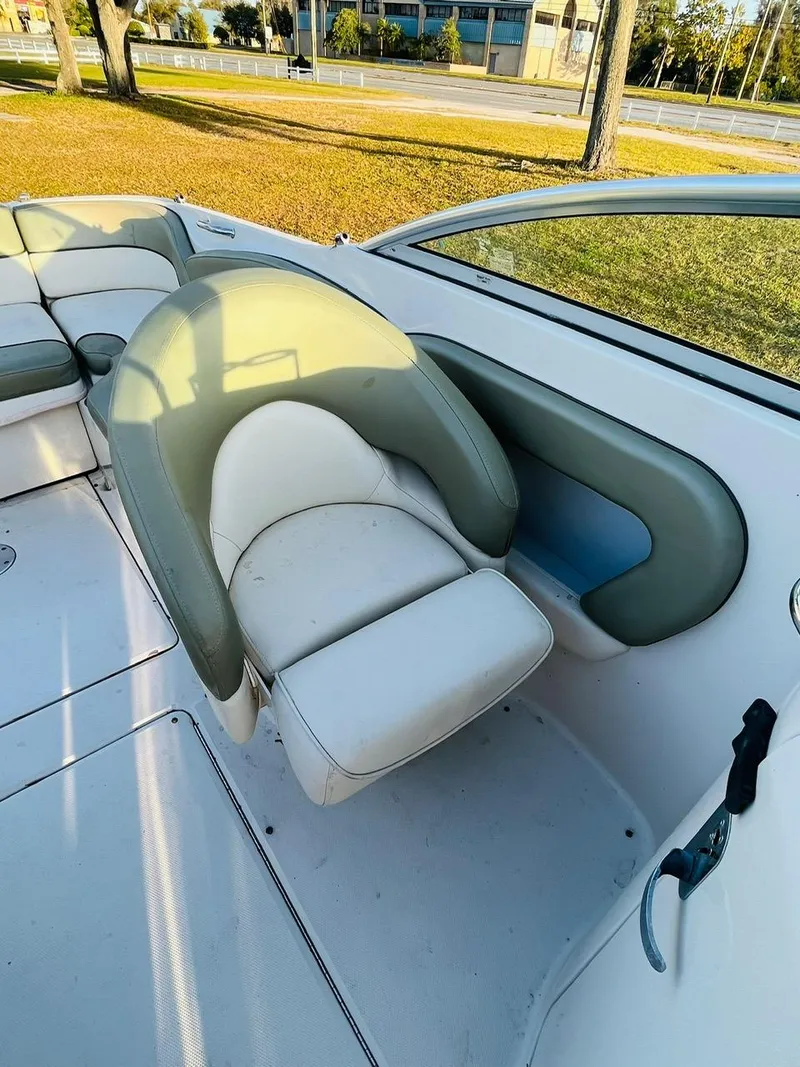 Slide: The Image of 2005 Sea Ray 240 Sundeck interior with white and green seating, outdoor setting. - 8