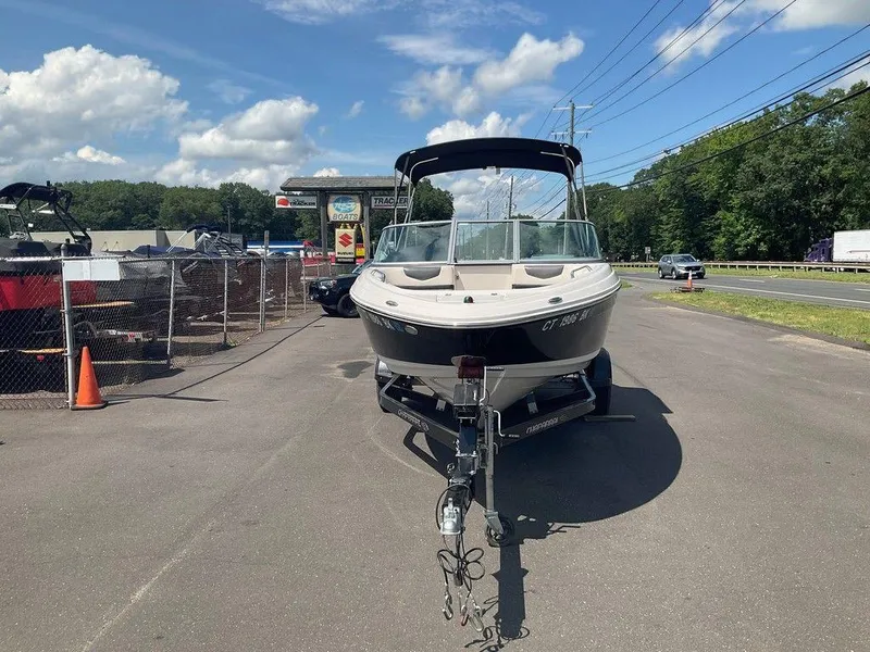 Slide: The Image of 2018 Chaparral 203 VR boat on trailer, parked near dealership, under clear blue sky. - 6