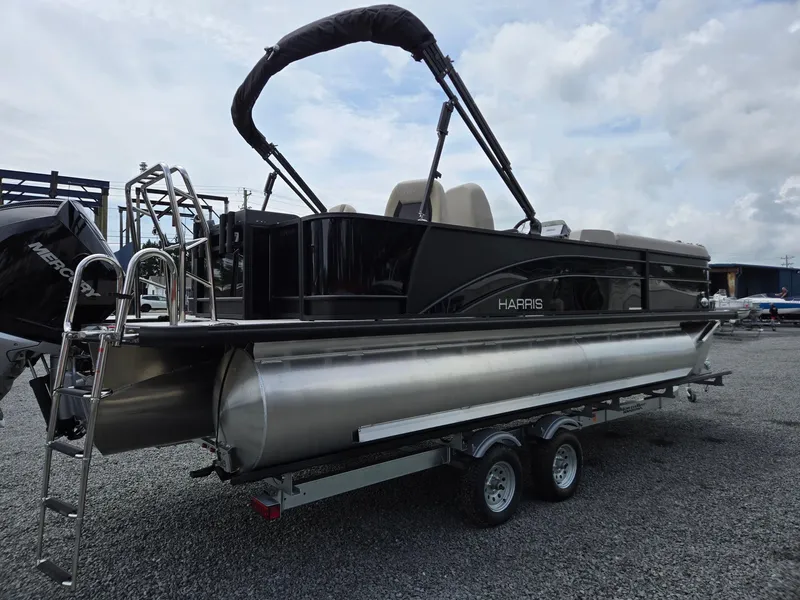 Slide: The Image of 2026 Harris Cruiser 230 pontoon boat on trailer, parked outdoors under cloudy sky. - 6