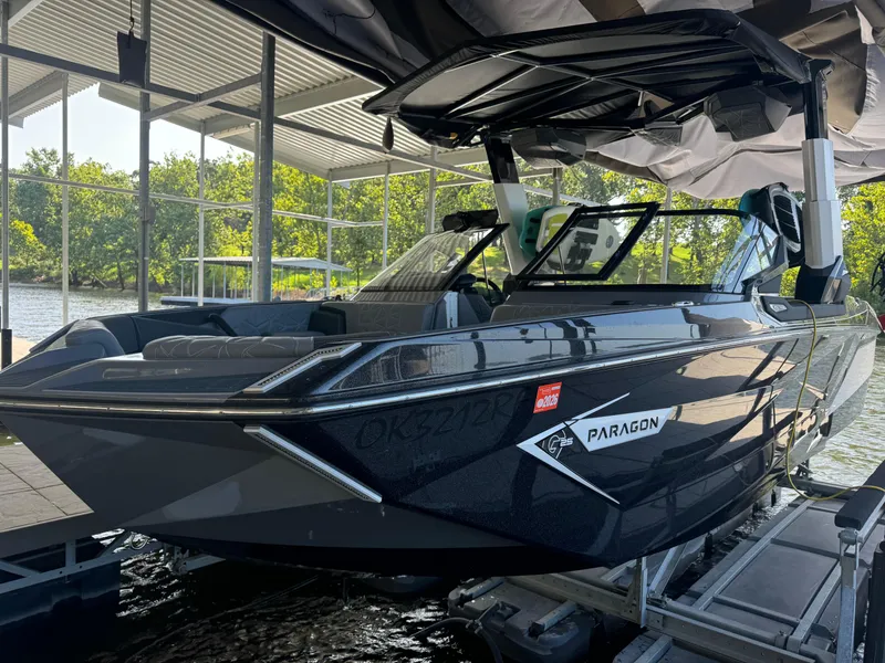 Slide: The Image of 2023 Nautique Super Air Nautique G25 Paragon boat docked under a canopy. - 2