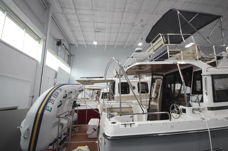 Slide: The Image of 2024 Ranger Tugs R-29 Command Bridge LE in indoor storage, featuring a dinghy and spacious deck. - 14