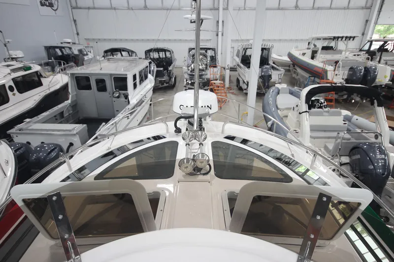 Slide: The Image of 2024 Ranger Tugs R-29 Command Bridge LE in a showroom, surrounded by other boats. - 24