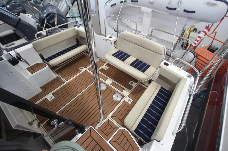 Slide: The Image of 2024 Ranger Tugs R-29 Command Bridge LE interior with cushioned seating and wood-style flooring. - 31