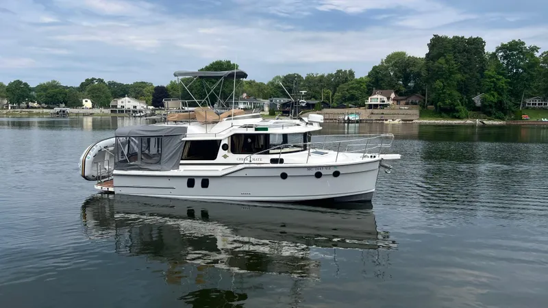 Slide: The Image of 2024 Ranger Tugs R-29 Command Bridge LE on a serene lake with lush shoreline. - 4
