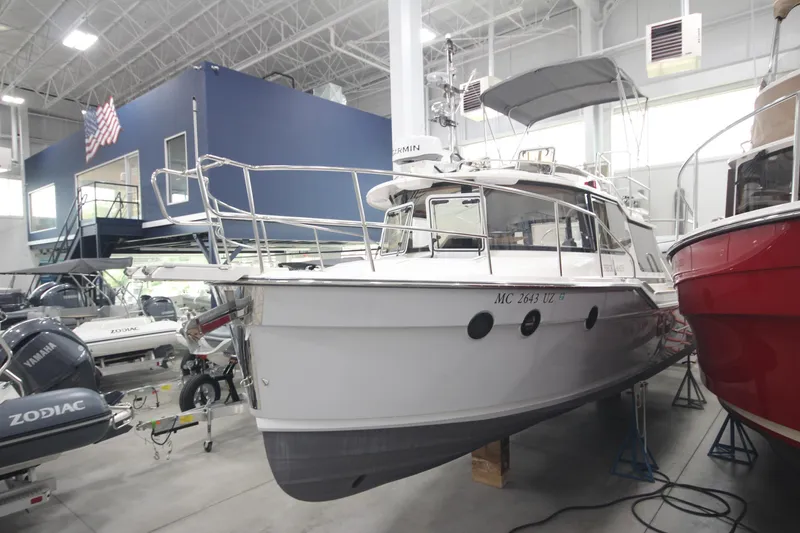 Slide: The Image of 2024 Ranger Tugs R-29 Command Bridge LE in showroom, surrounded by other boats. - 9
