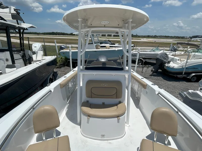 Slide: The Image of 2016 Sportsman Open 232 Center Console boat with beige seating, docked under a sunny sky. - 14