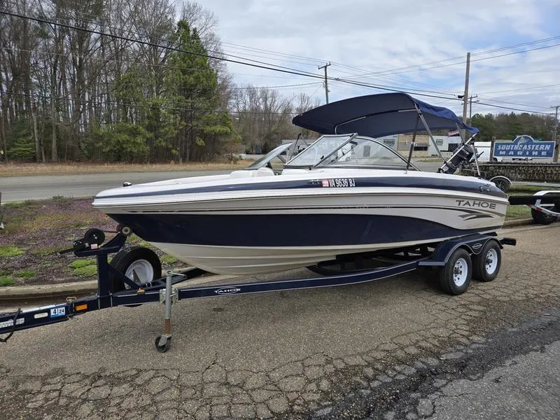 Slide: The Image of 2006 Tahoe Q6 boat on trailer with canopy, parked outdoors near trees and road. - 0