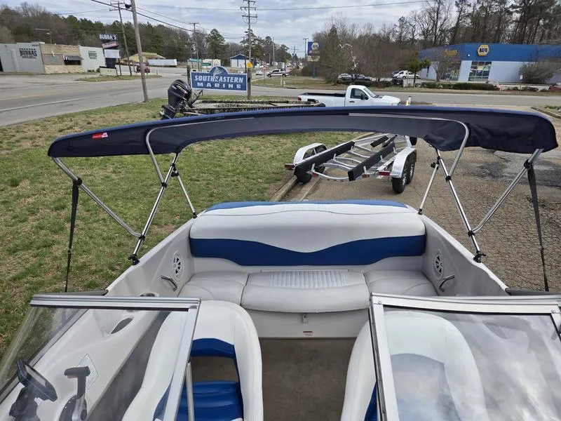 Slide: The Image of 2006 Tahoe Q6 boat with blue and white interior, parked near a road with a trailer. - 16