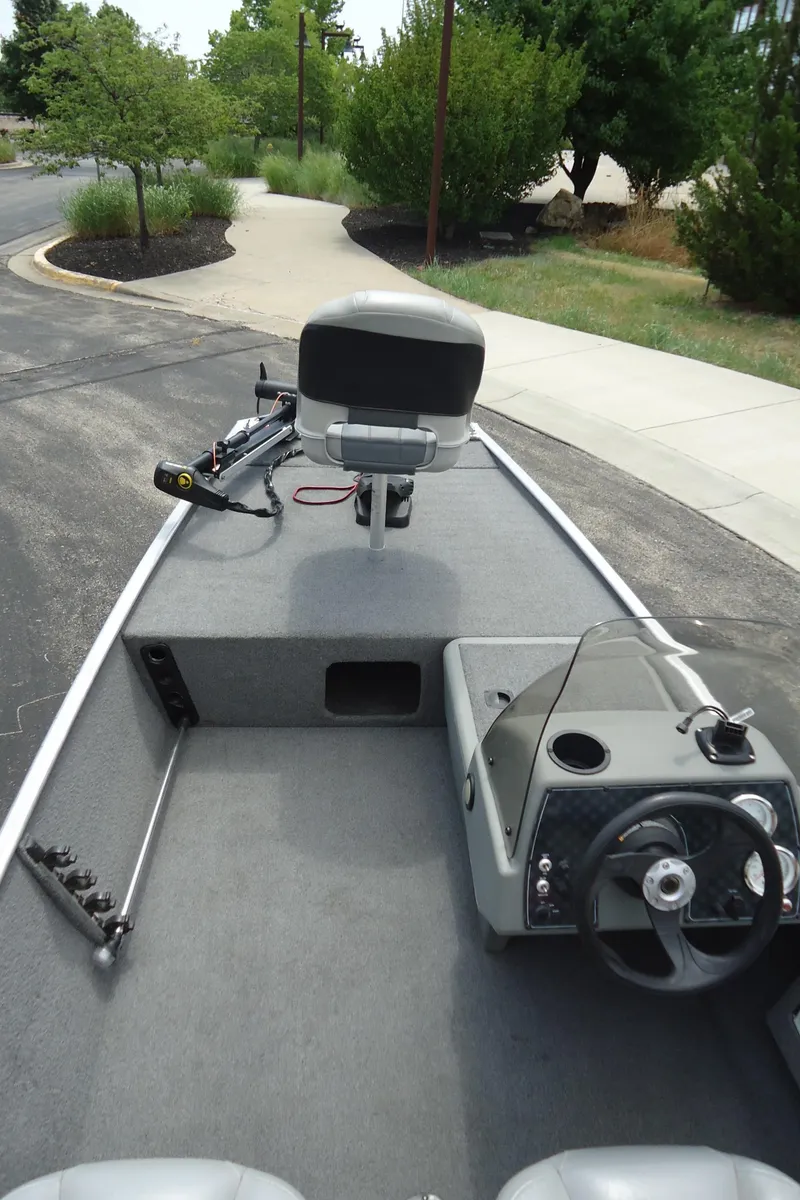 Slide: The Image of 2017 Tracker PRO160 boat interior with steering wheel and seating, parked on a paved area. - 3