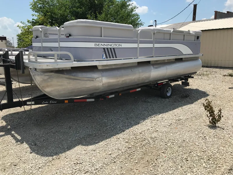Slide: The Image of 1998 Bennington 2050LX pontoon boat on trailer, parked on gravel lot. - 3