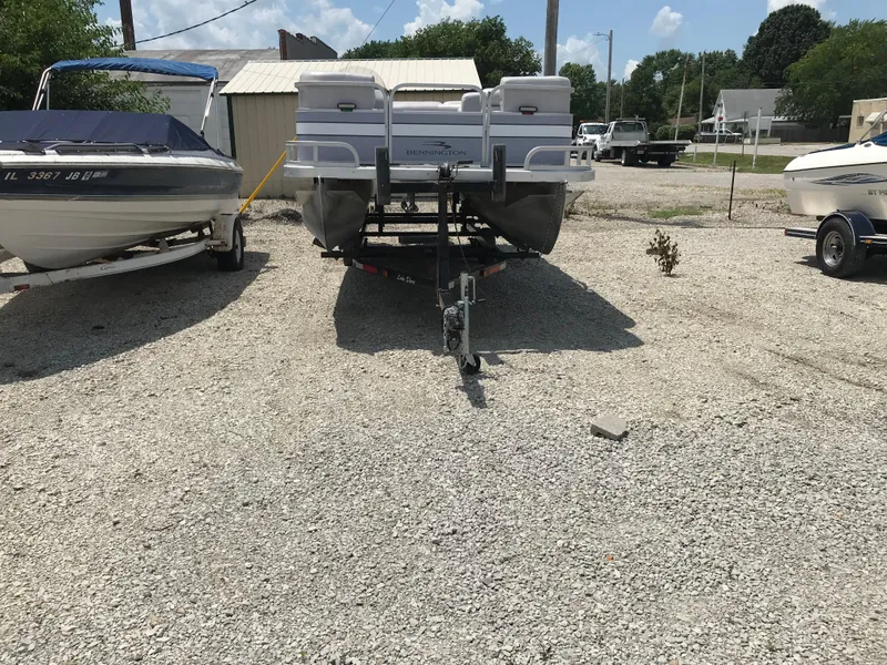 Slide: The Image of 1998 Bennington 2050LX pontoon boat on trailer, parked between two other boats. - 4