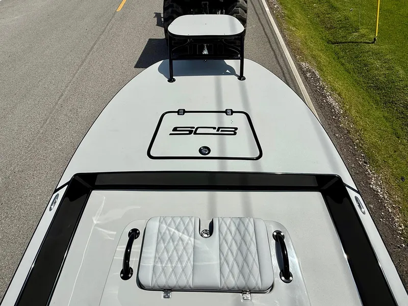 Slide: The Image of 2025 SCB R24 boat on trailer, top view, parked on roadside. - 13