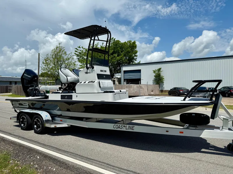 Slide: The Image of 2025 SCB R24 boat on trailer, parked outdoors under a partly cloudy sky. - 5