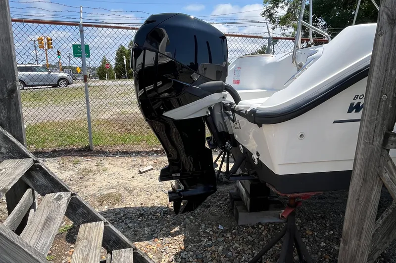Slide: The Image of 2005 Boston Whaler 210 Ventura boat with a black outboard motor, parked on gravel. - 30