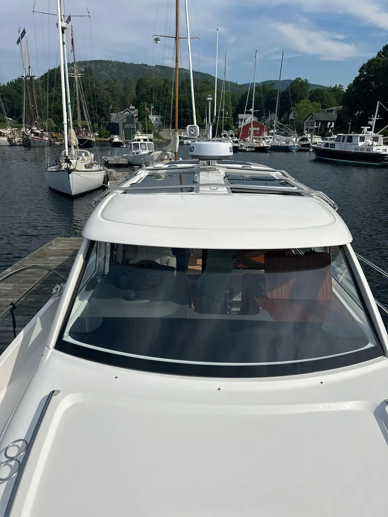 Slide: The Image of 2024 Nimbus 305 Coupe docked at a marina with sailboats and scenic background. - 48