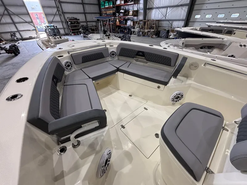 Slide: The Image of 2025 Cobia 285 Center Console boat interior with gray seating in a spacious warehouse. - 14