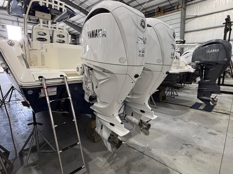 Slide: The Image of 2025 Cobia 285 Center Console with twin Yamaha outboard engines in a boatyard. - 2