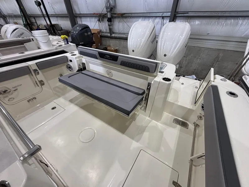 Slide: The Image of 2025 Cobia 285 Center Console boat interior with seating and dual engines in a warehouse. - 21