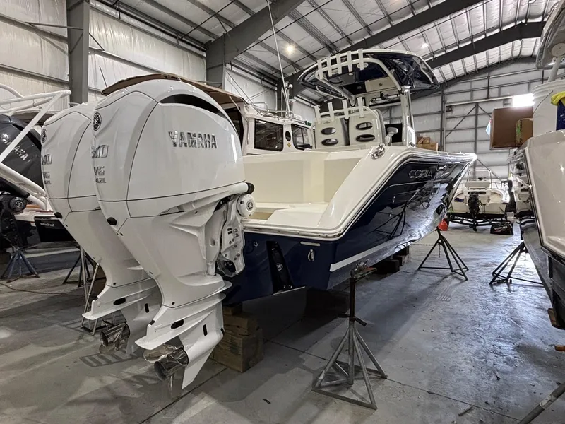 Slide: The Image of 2025 Cobia 285 Center Console boat with twin Yamaha engines in a storage facility. - 3