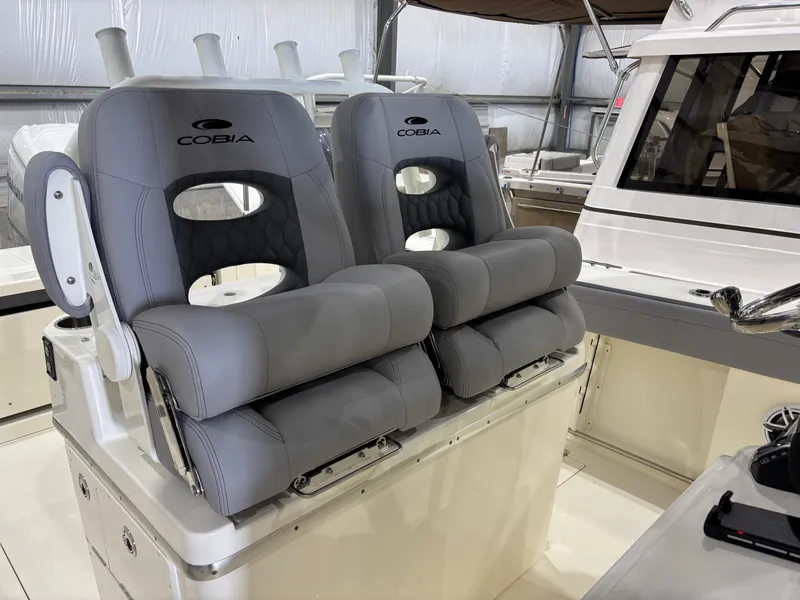 Slide: The Image of 2025 Cobia 285 Center Console boat with luxurious gray seating in a showroom. - 7