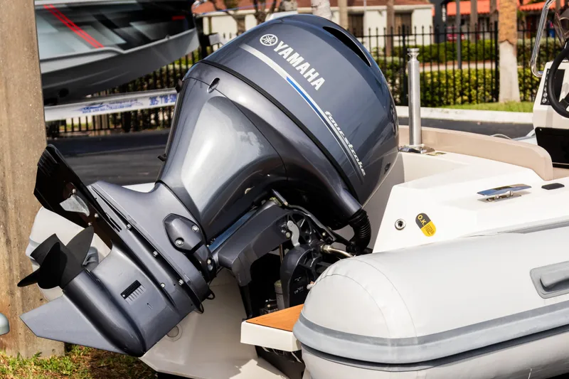 Slide: The Image of 2023 Northstar Axis 4.8 RIB with Yamaha outboard motor, docked outdoors. - 2