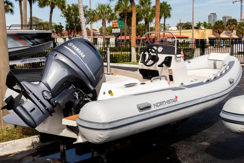 Slide: The Image of 2023 Northstar Axis 4.8 RIB boat with Yamaha outboard motor, parked outdoors. - 6