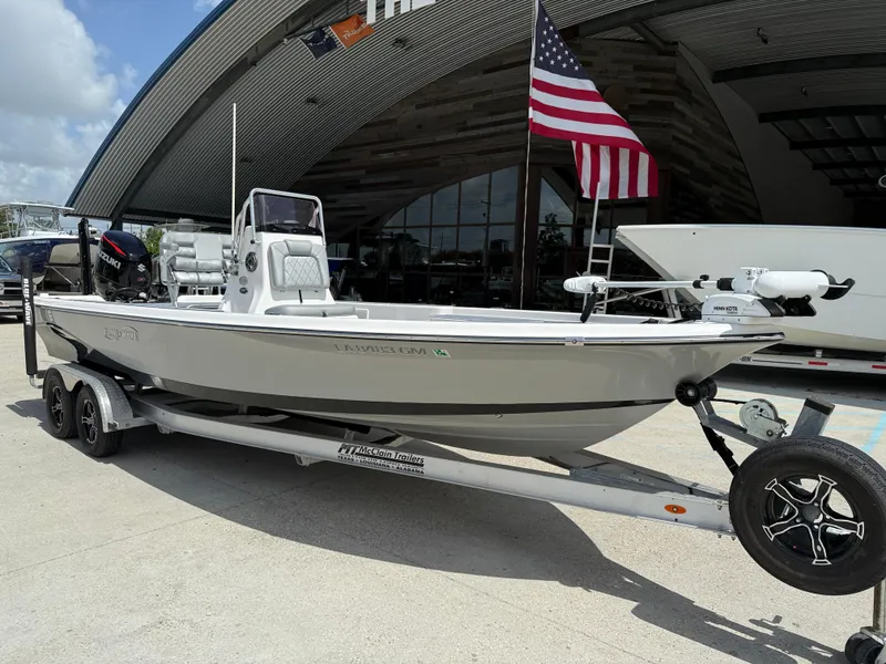 Slide: The Image of 2022 Blue Wave 2400 PureBay boat on trailer, front view, under clear sky. - 2