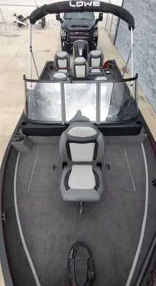 Slide: The Image of 2023 Lowe FM 1775 boat with seating and windshield, parked on concrete. - 11