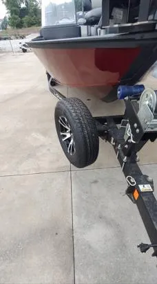 Slide: The Image of 2023 Lowe FM 1775 boat on trailer, featuring sleek red hull and modern wheel design. - 3