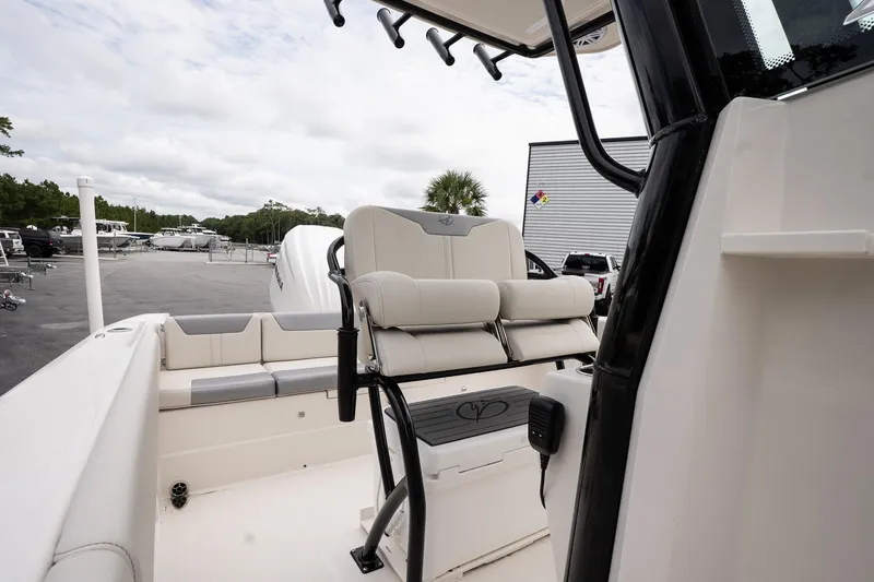 Slide: The Image of 2026 Sailfish 232 CC boat interior with seating and console, parked outdoors. - 13