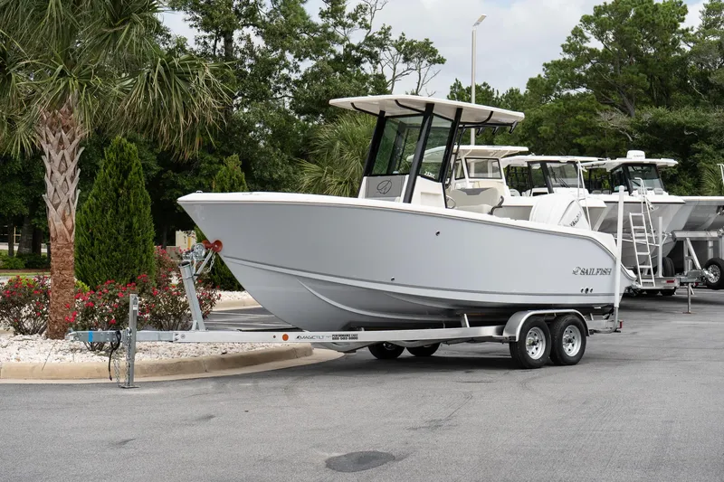 Slide: The Image of 2026 Sailfish 232 CC boat on trailer, parked near palm trees. - 2