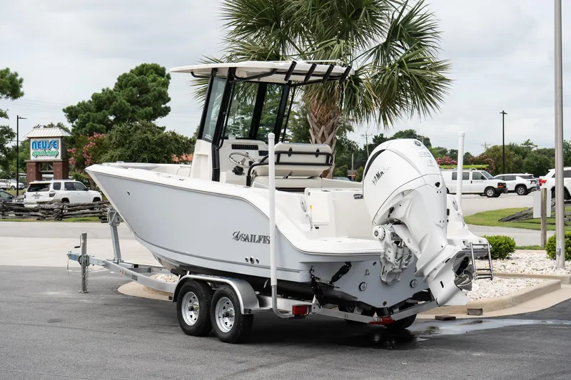 Slide: The Image of 2026 Sailfish 232 CC boat on trailer, parked near palm tree and shop. - 4