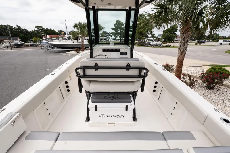 Slide: The Image of 2026 Sailfish 232 CC boat interior with seating and console, parked near palm trees. - 9
