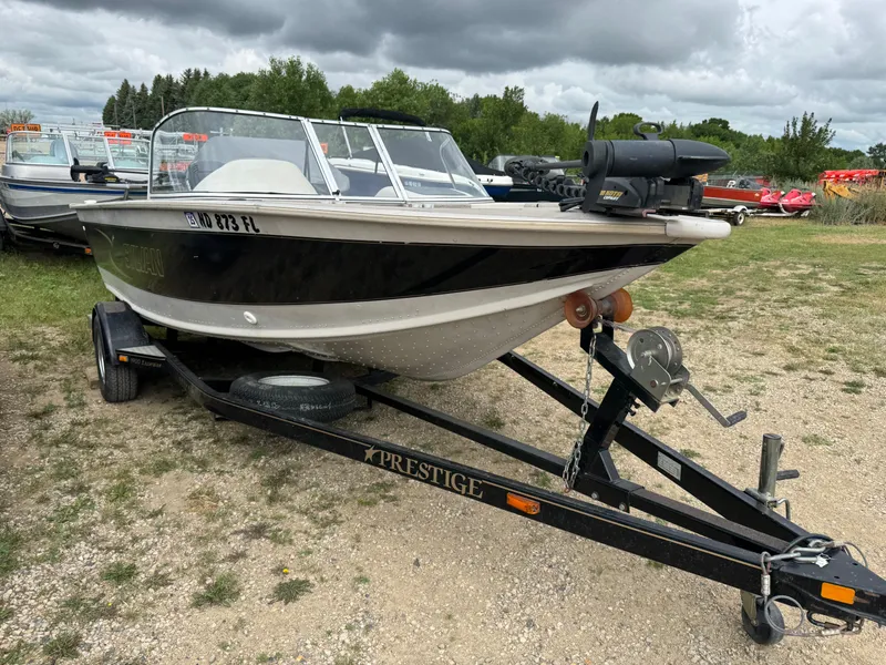 Slide: The Image of 2000 Sylvan 1900 Excursion boat on trailer, parked outdoors under cloudy sky. - 3