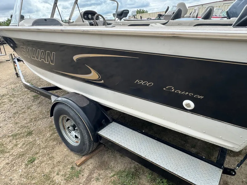 Slide: The Image of 2000 Sylvan 1900 Excursion boat on trailer, side view with logo and seating visible. - 6